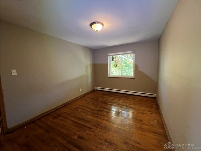 spare room with baseboard heating and dark hardwood / wood-style floors