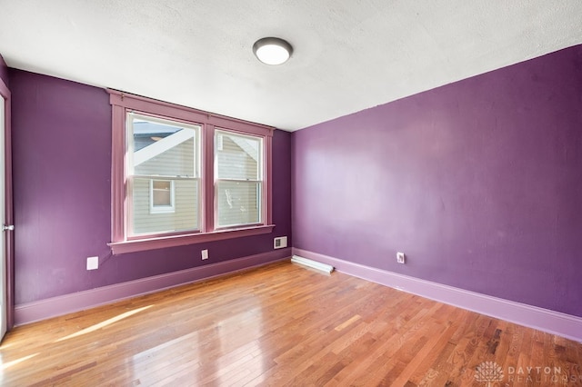 unfurnished room featuring hardwood / wood-style floors and a textured ceiling