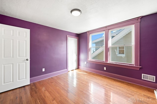 empty room featuring wood-type flooring and a textured ceiling