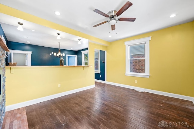 unfurnished living room with dark wood-type flooring and ceiling fan with notable chandelier