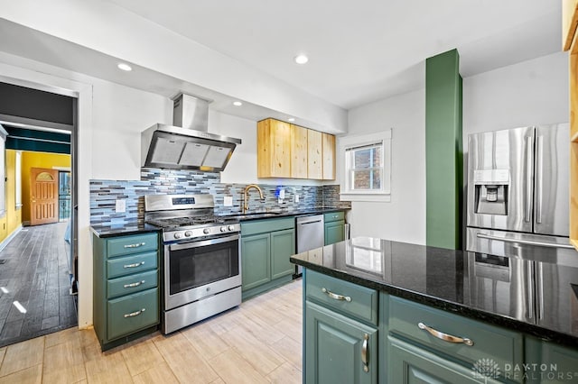 kitchen with green cabinets, sink, appliances with stainless steel finishes, wall chimney exhaust hood, and light wood-type flooring