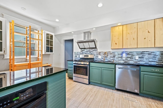 kitchen with stainless steel appliances, sink, tasteful backsplash, wall chimney exhaust hood, and light wood-type flooring