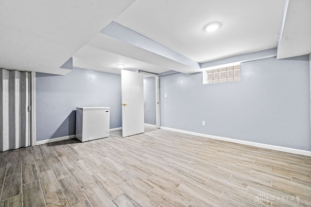 basement featuring light hardwood / wood-style flooring and refrigerator