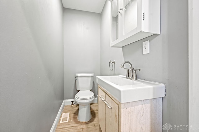 bathroom featuring toilet, vanity, and wood-type flooring