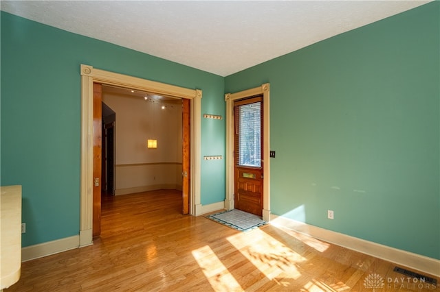 entryway with a textured ceiling and light hardwood / wood-style flooring