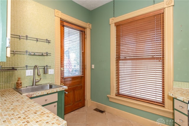 kitchen with a textured ceiling, sink, and light tile patterned floors