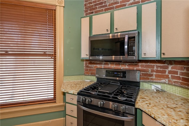 kitchen featuring brick wall, decorative backsplash, and stainless steel appliances