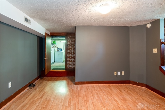 empty room with wood-type flooring, washer / dryer, and a textured ceiling