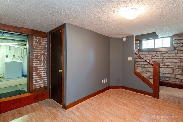 basement featuring washer / clothes dryer, a textured ceiling, and hardwood / wood-style flooring