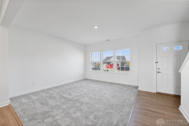 interior space featuring carpet flooring, wood finished floors, and baseboards