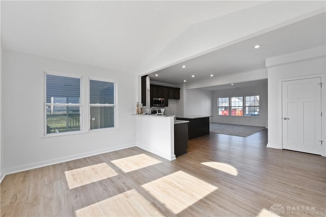 unfurnished living room with lofted ceiling, light wood-style floors, and baseboards