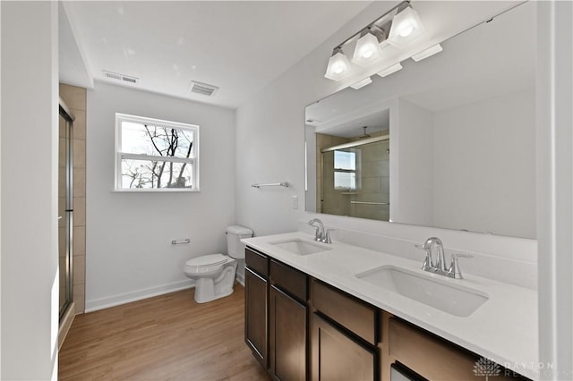 bathroom featuring a sink, visible vents, wood finished floors, and a shower stall