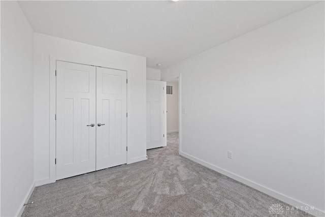 unfurnished bedroom with a closet, carpet flooring, and baseboards