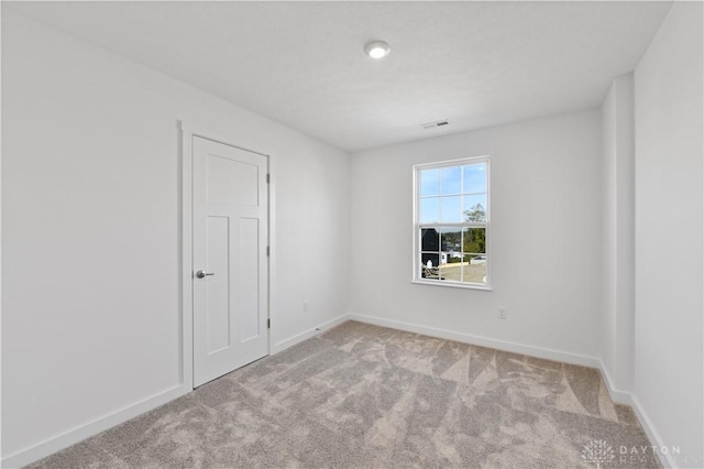 unfurnished room featuring baseboards, carpet floors, and visible vents