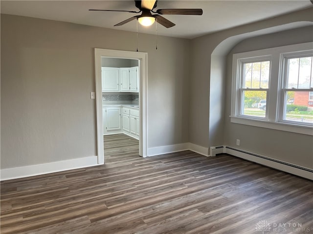 spare room featuring baseboard heating, hardwood / wood-style floors, and ceiling fan