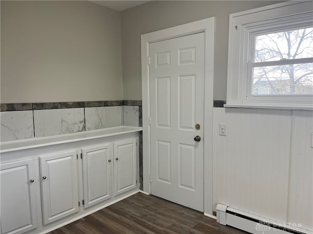 interior space with a baseboard heating unit and hardwood / wood-style flooring