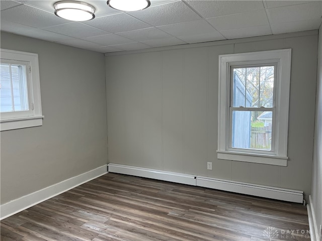 spare room featuring dark hardwood / wood-style flooring, a drop ceiling, and baseboard heating