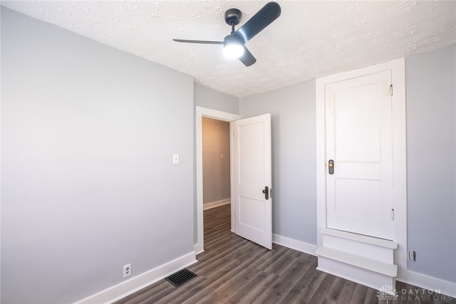 unfurnished bedroom featuring a textured ceiling, dark hardwood / wood-style flooring, and ceiling fan