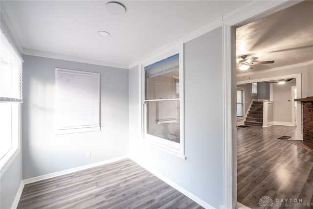 unfurnished room with a fireplace, wood-type flooring, ceiling fan, and crown molding