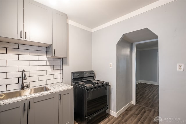 kitchen with dark wood-type flooring, sink, tasteful backsplash, ornamental molding, and black range with electric cooktop