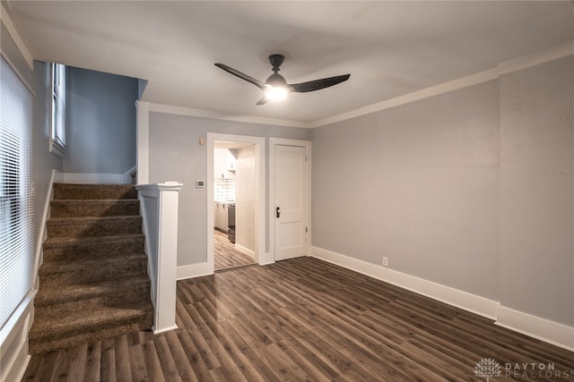 empty room featuring dark wood-type flooring, ornamental molding, ceiling fan, and plenty of natural light