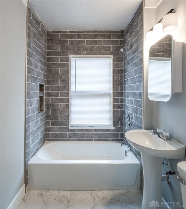 bathroom featuring toilet and tiled shower / bath