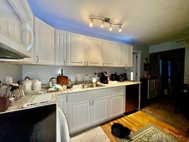 kitchen featuring stainless steel dishwasher, white cabinetry, sink, and light hardwood / wood-style flooring