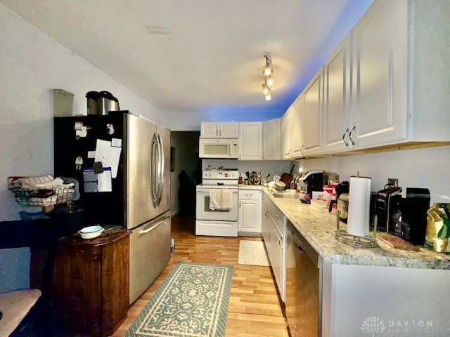 kitchen featuring stainless steel appliances, light hardwood / wood-style floors, light stone counters, white cabinets, and sink