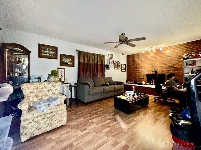 living room featuring track lighting, brick wall, hardwood / wood-style flooring, and ceiling fan