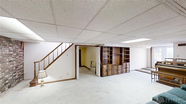 basement featuring brick wall and a drop ceiling