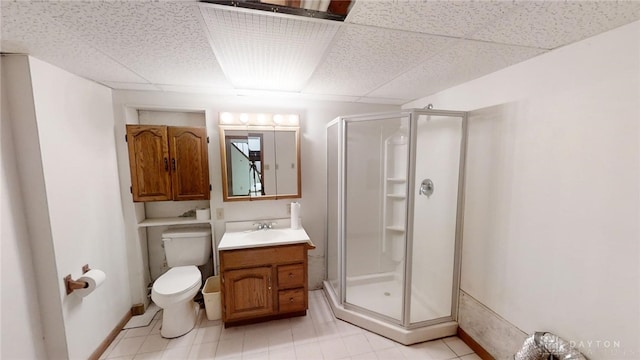 bathroom featuring toilet, a paneled ceiling, vanity, and a shower with door