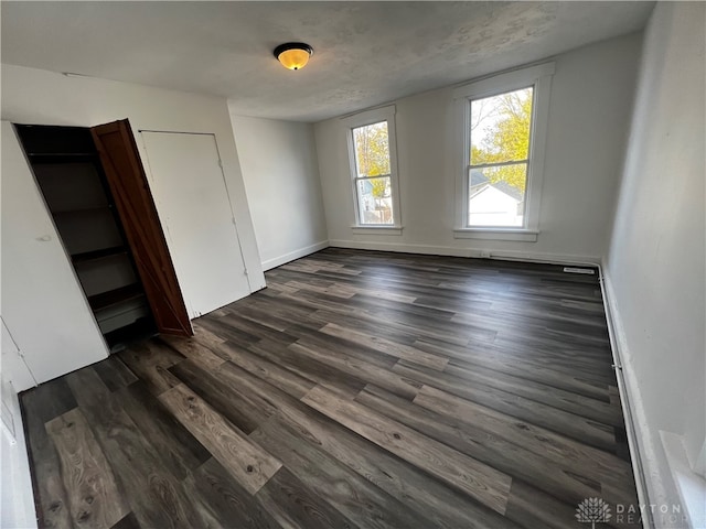 unfurnished room with dark hardwood / wood-style flooring and a textured ceiling