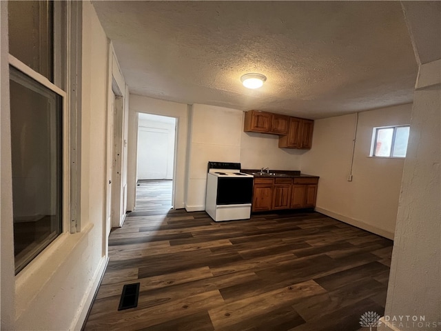 kitchen with dark wood-type flooring, a textured ceiling, sink, and electric range