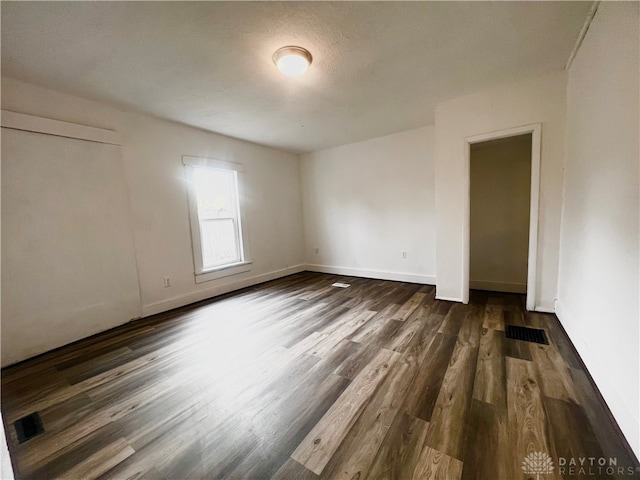 spare room featuring dark wood-type flooring and a textured ceiling