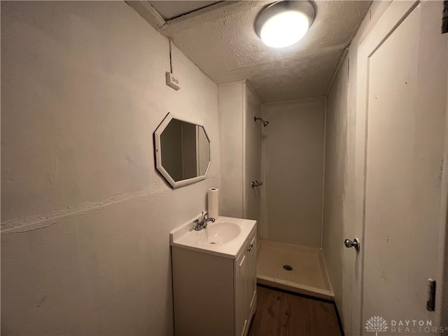 bathroom featuring a shower, vanity, hardwood / wood-style floors, and a textured ceiling