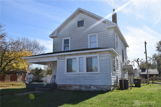 back of property with central AC and a lawn