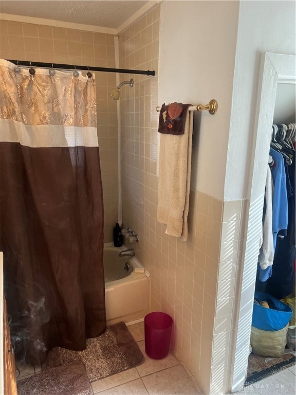 bathroom with a textured ceiling, tile walls, shower / bath combination with curtain, and tile patterned floors