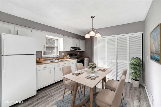 kitchen with pendant lighting, white cabinets, white refrigerator, sink, and electric range