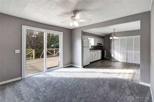 unfurnished living room with ceiling fan with notable chandelier and dark carpet