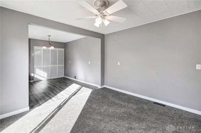 carpeted spare room featuring ceiling fan with notable chandelier