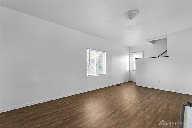 spare room with a textured ceiling and dark hardwood / wood-style floors