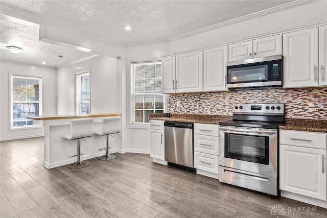 kitchen featuring a textured ceiling, appliances with stainless steel finishes, and white cabinets