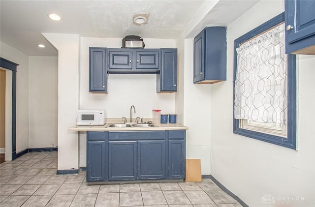 kitchen with blue cabinetry, sink, and light tile patterned floors