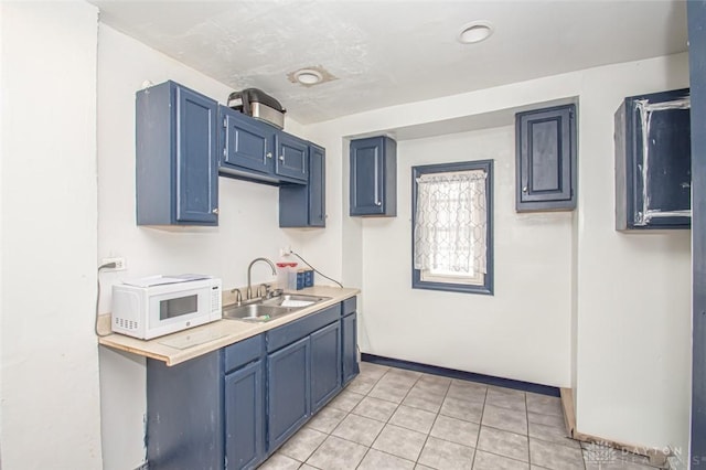 kitchen featuring light tile patterned flooring, blue cabinets, and sink