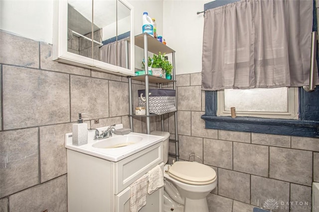 bathroom featuring vanity, toilet, and tile walls