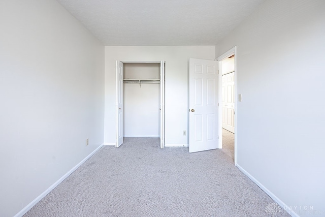 unfurnished bedroom featuring light carpet and a closet