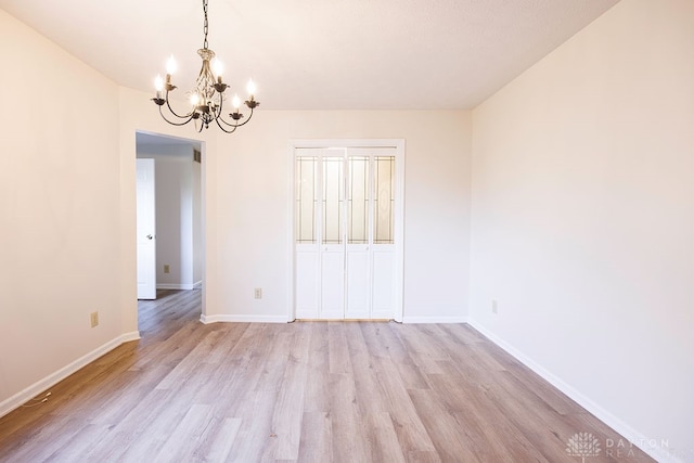 unfurnished room featuring an inviting chandelier and light wood-type flooring