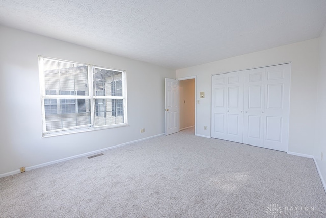 unfurnished bedroom featuring a closet and light colored carpet