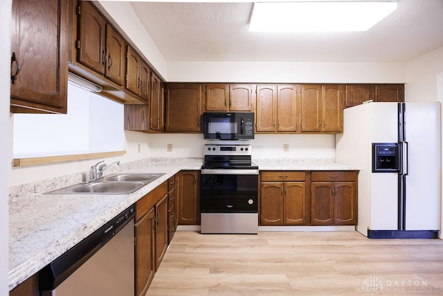 kitchen with light hardwood / wood-style floors, a textured ceiling, sink, and appliances with stainless steel finishes