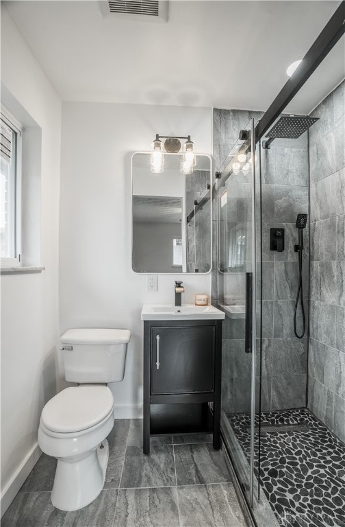 bathroom with vanity, toilet, and a shower with door